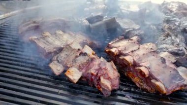 Bir Aşçı Barbeküler Sığır Eti Kuzu ve Domuz bir parti 4k Yavaş hareket için bir sos marine ile ateşte büyük Izgara Kaburga bir sürü hazırlar