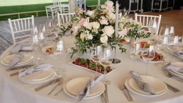 흰색 테이블 보와 큰 테이블 연회 는 맛있는 요리, 결혼식을위한 꽃 꽂이 촛불 장식을 모듬. 카메라 모티온 4k 슬로우 모션. — 비디오