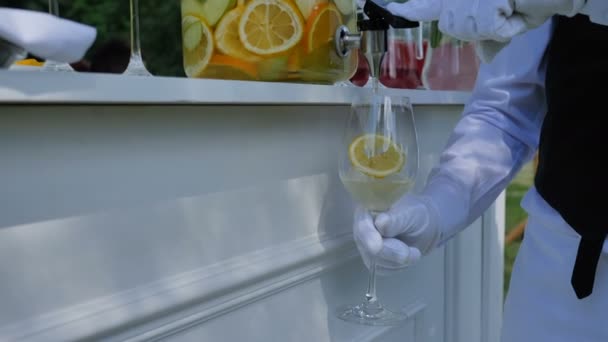 Kelner wylewa cytrusowych lemoniady pomarańcze lemoniady do szklanki dla Gości na wesele lub przyjęcie urodzinowe — Wideo stockowe