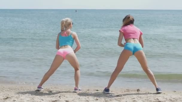 Девочки занимаются спортом на фоне моря — стоковое видео