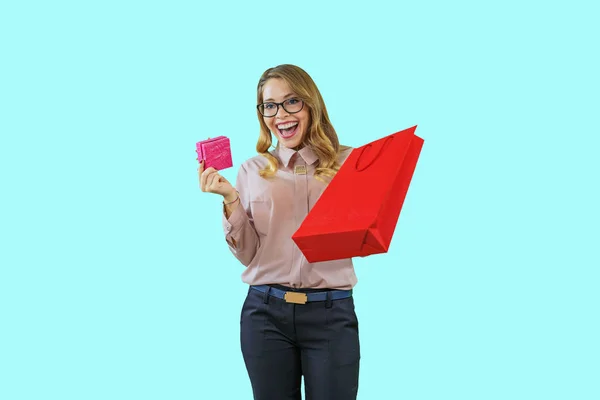 Portrait of a young beautiful blonde in glasses holding in one hand a small box in the other hand a package shouts yes yes yes on an isolated background, New Year holidays, birthday, marriage proposal — 图库照片