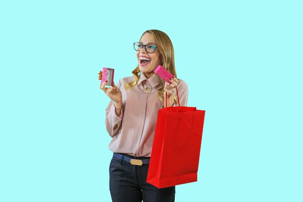 Portret van een jonge mooie blonde in glazen houdt in de ene hand een kleine doos openen en glimlachend enthousiast brede open mond in de andere hand een pakket op een geïsoleerde achtergrond, Nieuwjaar — Stockfoto