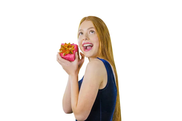 Retrato de uma jovem ruiva que fica meia volta segurando uma pequena caixa com um presente em seu rosto com as duas mãos e emocionalmente se alegra sorrindo e abrindo a boca bem aberta olhando para cima em um — Fotografia de Stock