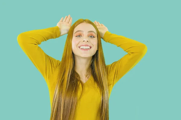 Portrait of a young beautiful schoolgirl with long red hair and with make-up of a girl with a playful mood, imitating ears with a smile and hands on her head — Φωτογραφία Αρχείου