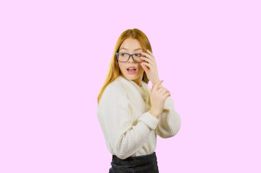 Gözlüklü sevimli, genç kızıl saçlı bir kız, elinde gözlüklerle profilde duruyor, şaşırmış, izole edilmiş arka plan