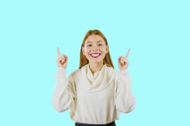 Uzun kızıl saçlı genç güzel kız iki işaret parmakları kaldırdı ve kameraya bakarken gülümseyerek, bir zafer ve neşeli duygular duygu