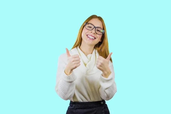 Retrato de uma linda menina de cabelos vermelhos em óculos e uma camisola branca mostrando classe com ambas as mãos sorrindo com a cabeça inclinada para o lado olhando para a câmera em um fundo isolado, moda — Fotografia de Stock