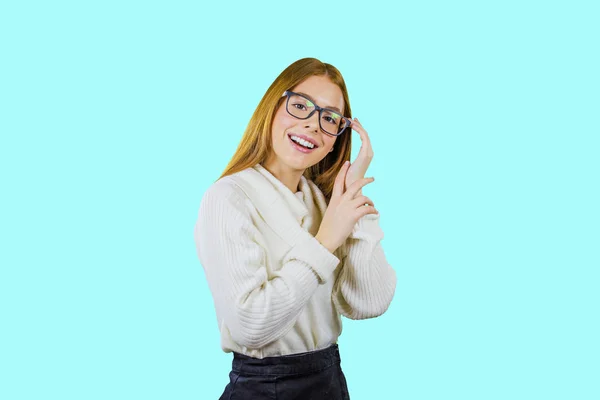 Porträt eines netten rothaarigen Mädchens mit Brille und weißem Pullover, das mit einer Hand eine Brille hält und die andere Hand auf die erste legt, lächelnd und isoliert in die Kamera blickt — Stockfoto