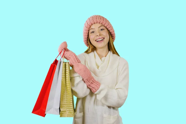 Attraktive Mädchen mit langen roten Haaren in einem weißen Pullover mit einem Lächeln hält Pakete mit Geschenken auf einem isolierten Hintergrund — Stockfoto