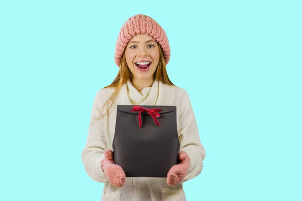 A lány a hosszú vörös hajú, fehér pulóvert egy mosolyt tart fekete ajándék egy elszigetelt háttér — Stock Fotó