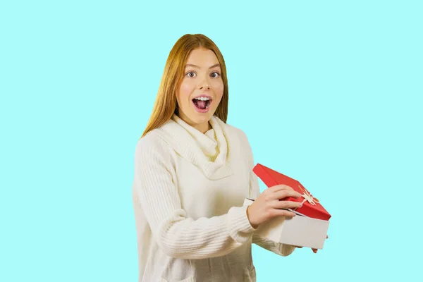 Menina alegre em uma camisola branca com um presente na mão em um fundo isolado — Fotografia de Stock