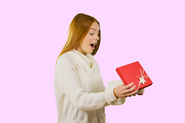 Kırmızı saçlı çekici kız zevk ile izole bir arka plan üzerinde hediye açar — Stok fotoğraf