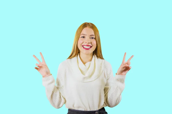 Ein junges Mädchen mit langen roten Haaren zeigt Pisse mit beiden Händen, die sie vor einem isolierten Hintergrund lächelnd hochhalten — Stockfoto