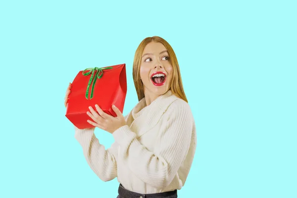 Portré egy gyönyörű aranyos vörös hajú lány, aki rendelkezik egy ajándék táska egy doboz piros, zöld bársony szalagot emelés az ajándékot mutatja a mosolygó lelkesen felnézett az oldalára ellen — Stock Fotó