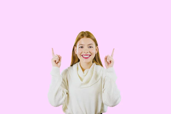 Young beautiful girl with long red hair raised up two index fingers and smiling while looking into the camera, a sense of happiness — Stock Photo, Image