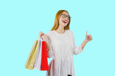Gözlük genç bir güzel kızıl saçlı kız portresi ve yeni satın alma lar veya hediyeler paketleri ile, hangi yan bakarak sevinç duygularını gösterir ve sınıf gösterir, izole bir fotoğraf