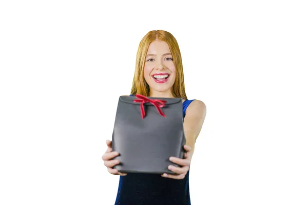 Uma menina bonita com cabelos longos vermelhos está segurando uma caixa exclusiva preta com um presente e sorrindo para a câmera. O conceito de presentes de férias e compras — Fotografia de Stock