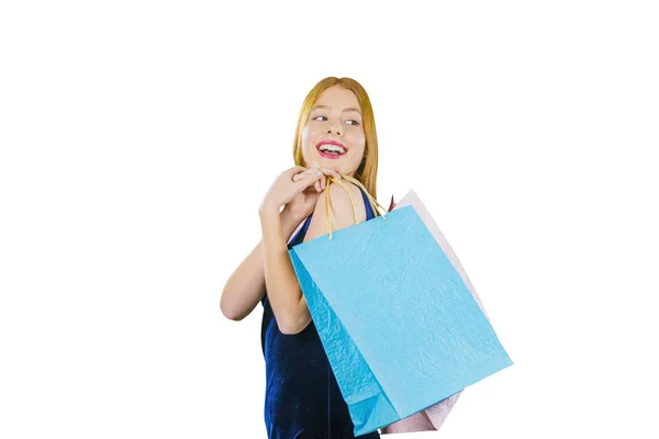 Une jeune fille aux longs cheveux roux tient deux sacs par-dessus son épaule avec de nouveaux achats d'une valeur d'un demi-tour et sourit en regardant par-dessus son épaule, photo rapprochée — Photo