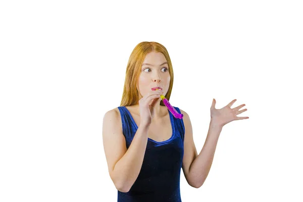 Un portret al unei fete frumoase cu păr lung și roșu, care ține o țeavă festivă cu o panglică în gură și se îndoaie în ea și este surprinsă privind în lateral în timp ce își ridică celălalt braț îndoit la — Fotografie, imagine de stoc