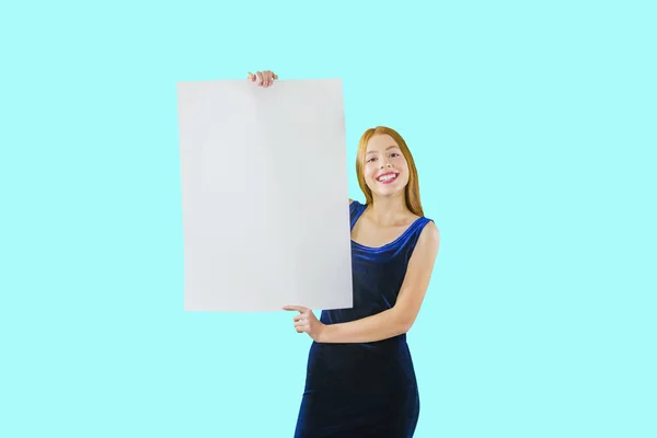 Portrait of a young red-haired girl who holds both hands along the length of the poster looking at the camera and smiling with white teeth on an isolated background — Stock Photo, Image