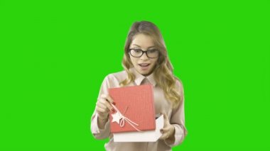 Elinde bir hediye ile bir kutu tutan neşeli genç kız açar ve duygusal izole yeşil bir arka plan üzerinde hayran