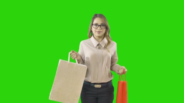 Joyful delight of a young woman shopaholic shopping on an isolated green background — Stock Video