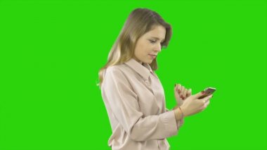 Saten bluzlu genç güzel kadın elinde bir akıllı telefon tutuyor, orada bir şey arıyor, ve sonra gülümseyerek ve sınıf gösteren, izole bir arka plan üzerinde filme