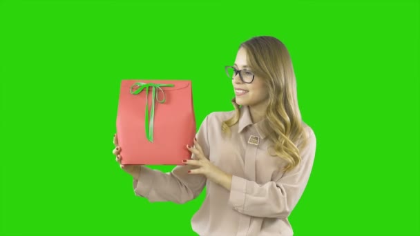 Joyful emotions of a young woman who rejoices at a gift, a gift in a red box with a green ribbon, filming on an isolated background — Stock Video