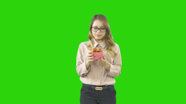 Blonde girl holding a small box with a gift or with a ring is smiling and does not dare to open, shooting on an isolated background — Stockvideo