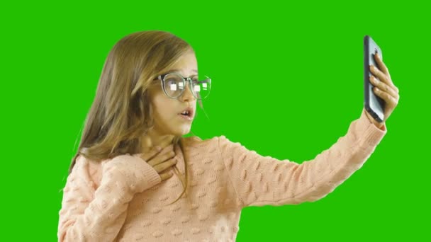 En skolåldern flicka som håller en telefon ser in i det och är förvånad, upprörd med uttalade känslor, isolerad bakgrund — Stockvideo