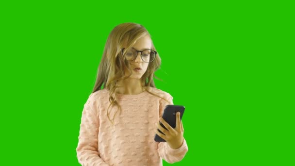 Jolie fille avec de longs cheveux bouclés rozgovarivat sur le smartphone par lien vidéo, souriant à vérifier, filmant sur un fond isolé — Video