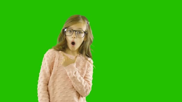 Legrační malá blondýnka ve skleničkách s brýlemi, která ukazuje něco s prsty, ukazuje její překvapení, natáčení na izolovaném pozadí — Stock video