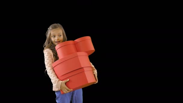 Uma menina bonita pouco de cerca de dez goza de presentes emocionalmente sorrindo carrega três caixas na forma de corações, feriados, feriados de Ano Novo, aniversário — Vídeo de Stock