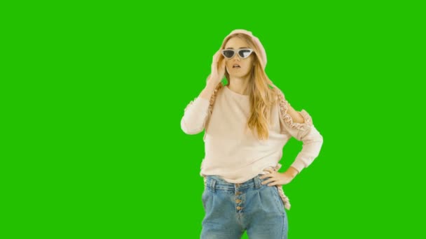 Jeune blonde séduisante en vêtements et lunettes tendance sourit agréablement et avec enthousiasme, prise de vue de mode, fond vert — Video