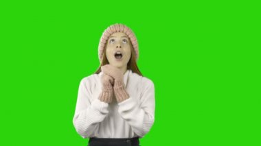 Pembe şapkalı genç sevimli kızıl saçlı kız ve eldivenler ellerini gökyüzüne kaldırır ve gülümseyen ve sevinen hayran, izole bir arka plan üzerinde moda çekim