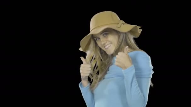 Ελκυστική γυναίκα με μακριά μαλλιά σε ένα καπέλο στέκεται στο προφίλ γυρίζει χαμογελώντας και αναβοσβήνει με ένα μάτι, Μόδα γυρίσματα σε ένα απομονωμένο φόντο — Αρχείο Βίντεο