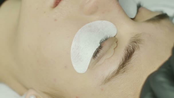 Primer plano de los ojos de las mujeres con una almohadilla selekon sobre el párpado, el maestro del salón aplica un gel a una almohadilla de silicona. pestañas, primer plano, macro, belleza femenina — Vídeos de Stock