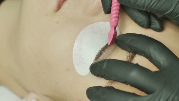 Schönheitssalon, Wimpernverlängerungen. Weibliche Augen schließen sich mit selekonovoy überlagertem Augenlid. der Meister des Salons presst die Wimpern mit Hilfe eines speziellen Spachtels gegen die Augenbraue — Stockvideo