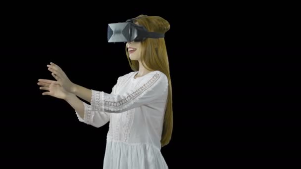 Colegiala con el pelo rojo en gafas 3D es en realidad virtual, una visita guiada con fines de aprendizaje, un juego virtual, disparar sobre un fondo aislado — Vídeos de Stock
