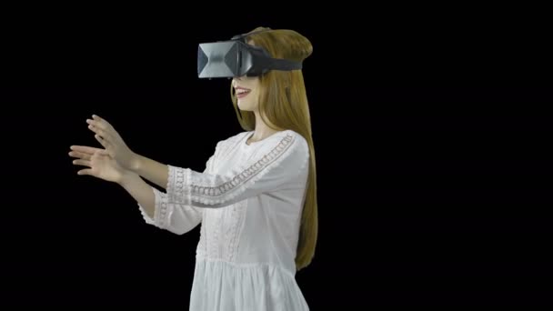 Colegiala con el pelo rojo en gafas 3D es en realidad virtual, una visita guiada con fines de aprendizaje, un juego virtual, disparar sobre un fondo aislado — Vídeo de stock