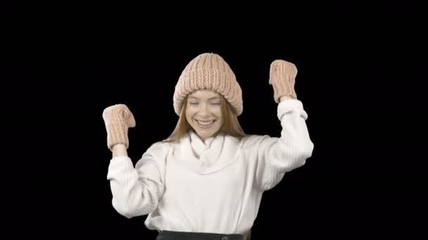 Красивая молодая девушка с длинными рыжими волосами в вязаной шляпе и рукавицах выражает эмоции победы размахивая руками и говоря да, модные съемки, Новый год съемки на изолированной — стоковое видео