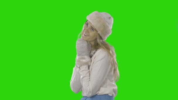 Элегантная красивая молодая женщина в шляпе, рукавицах и свитере с вышитыми камнями рядом с шеей показывает, что касается, держа обе руки рядом с лицом, модная фотография на изолированном фоне — стоковое видео