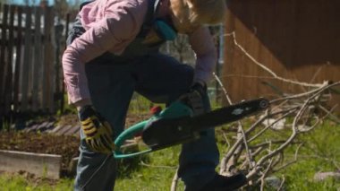 Bahçede ağaç kesen orta yaşlı bir kadın.