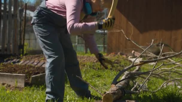 Зрелая женщина рубит ветви топора — стоковое видео