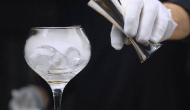Kuru buzla yakın içecekler. Barmen şarap kadehinde buzlu kokteyl hazırlıyor. Cam buharla kaplanmış.