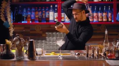 Barmen şişe ve çelik karıştırıcı ile hokkabazlık yapıyor.
