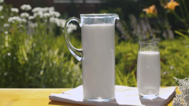Кувшин и стакан молока в саду — стоковое видео