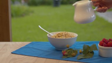 Müsli dolu bir kaseye süt dökülüyor.