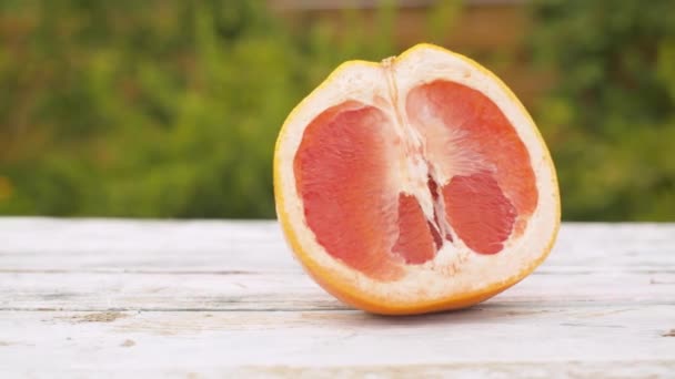 Половина червоного апельсина рухається вздовж столу — стокове відео