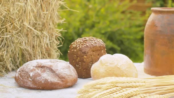 Chlebové bochníky, pšeničné uši a hliněný hrnec — Stock video